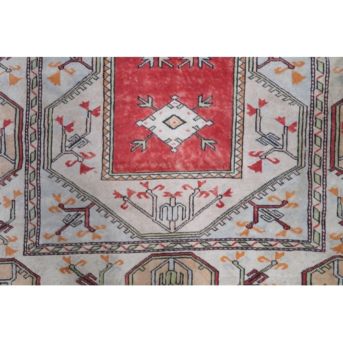 50 - A beige ground Turkish rug with red central column within geometric patterned ground with multicolou... 