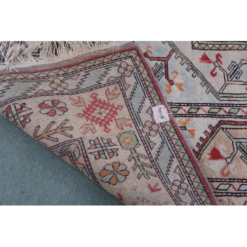 50 - A beige ground Turkish rug with red central column within geometric patterned ground with multicolou... 