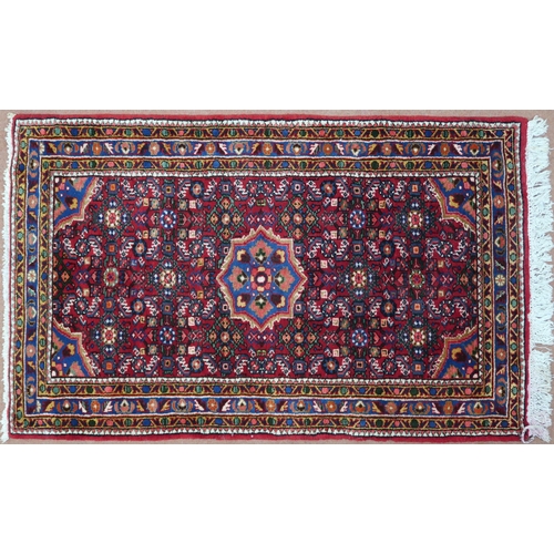 87 - A red ground Hamadan rug with blue central medallion, matching spandrels and multicoloured borders, ... 