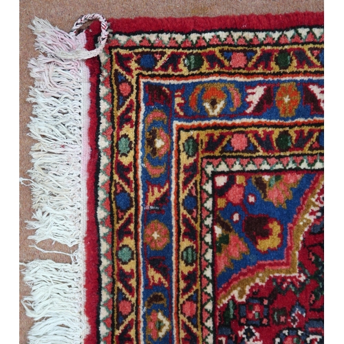 87 - A red ground Hamadan rug with blue central medallion, matching spandrels and multicoloured borders, ... 