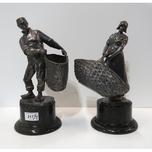 217 - A pair of spelter figures of a Dutch man and woman, carrying large baskets, on marble bases