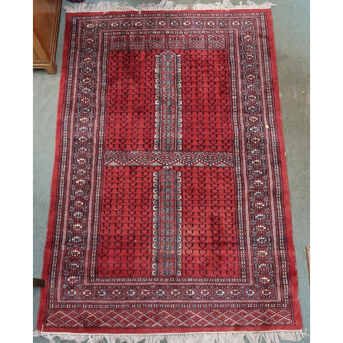 24 - A red ground Turkaman rug with four panelled ground with multicoloured geometric border, 190cm long ... 