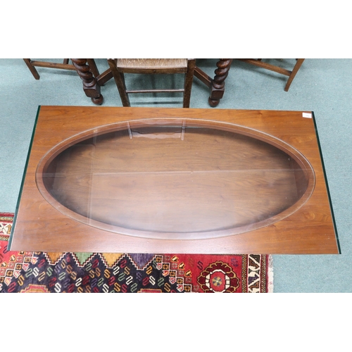 101 - A mid/late 20th century stained teak and glass coffee table with oval glass inset top over shelf on ... 