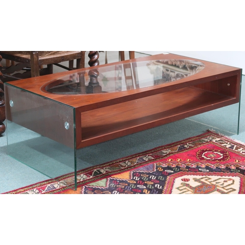 101 - A mid/late 20th century stained teak and glass coffee table with oval glass inset top over shelf on ... 