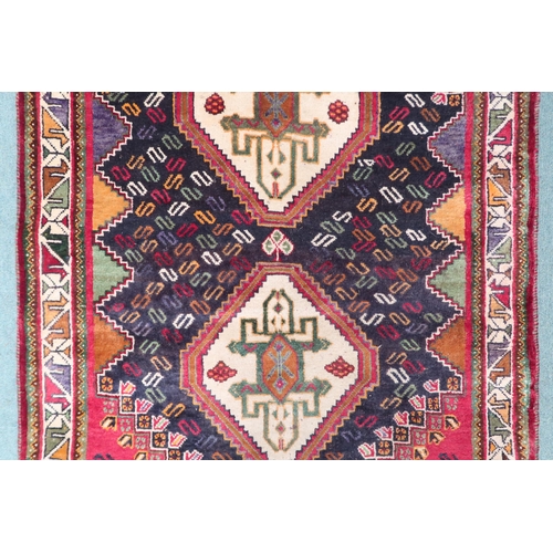 36 - A dark blue ground Balouch rug with pair of cream geometric medallions, red spandrels and cream geom... 
