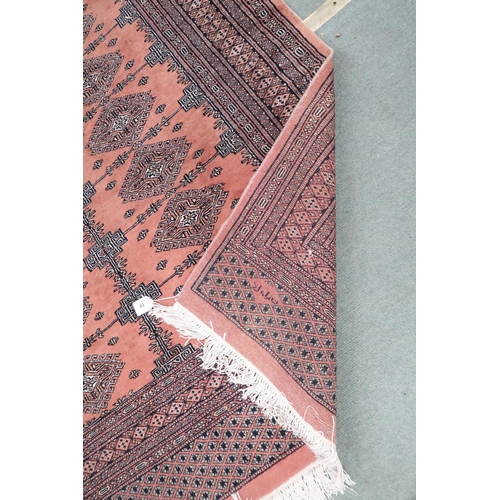 53 - A pink ground Bokhara rug with lozenge patterned ground and multiple borders, signature to corner, 1... 