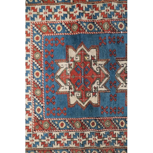 55 - A blue ground Shirvan rug with three terracotta and cream medallions and multicoloured geometric bor... 