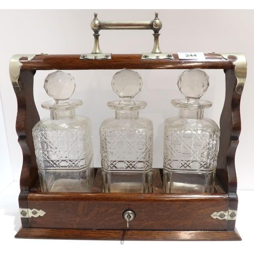 244 - A three bottle decanter in wooden stand with silver plated mounts