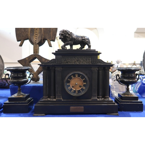 182 - A slate mantle clock with spelter Medici lion finial with a pair of urn shaped garnitures