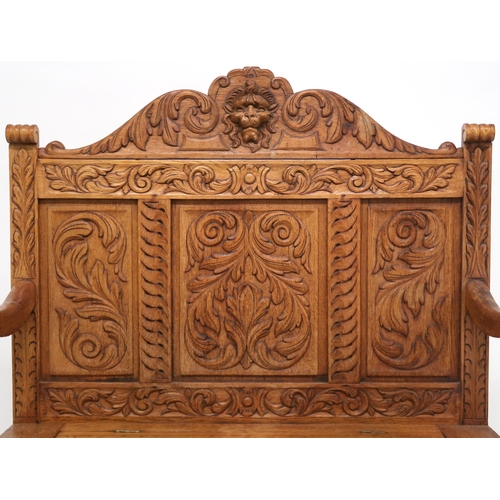 2053 - AN EARLY 20TH CENTURY CARVED OAK HALL SETTLE with lion masque surmount other carved foliate pan... 