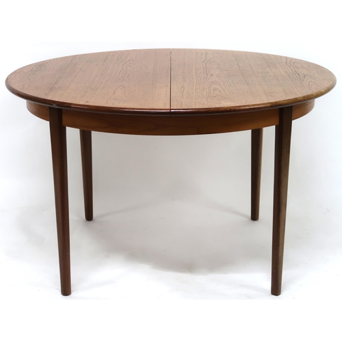 2102 - A MID 20TH CENTURY TEAK EXTENDING DINING TABLE AND SIX CHAIRS with circular extending top over inter... 