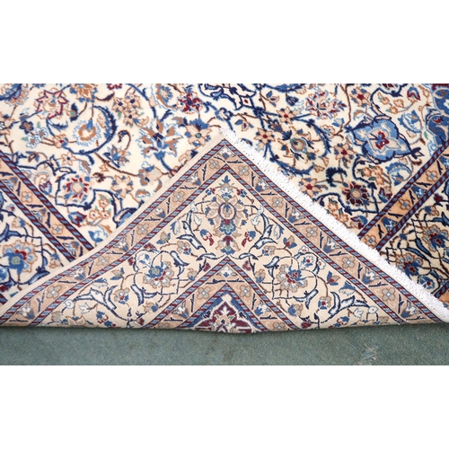 2134 - A CREAM GROUND NAIN RUG with a blue and red central medallion, matching spandrels on all-over floral... 