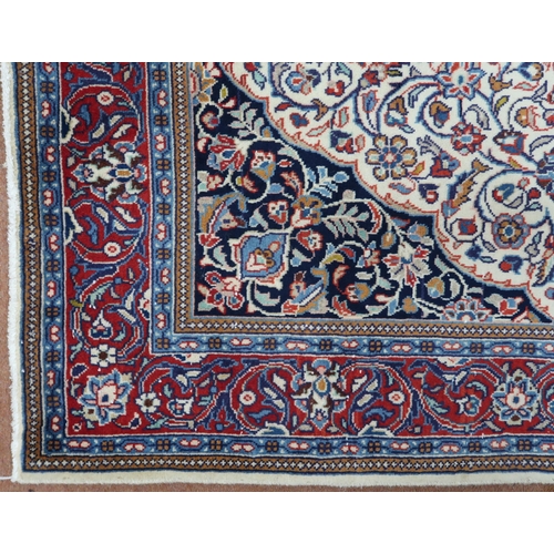 2137 - A CREAM GROUND KASHAN RUG with yellow and blue central medallion and dark blue spandrels on a floral... 