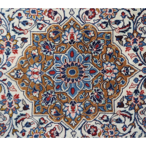 2137 - A CREAM GROUND KASHAN RUG with yellow and blue central medallion and dark blue spandrels on a floral... 