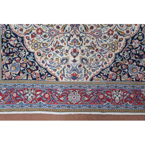 2137 - A CREAM GROUND KASHAN RUG with yellow and blue central medallion and dark blue spandrels on a floral... 