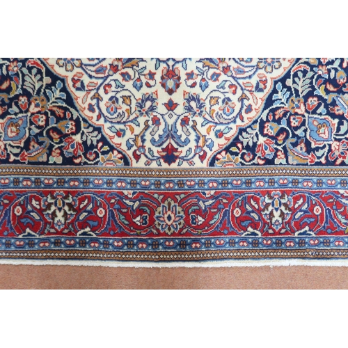 2137 - A CREAM GROUND KASHAN RUG with yellow and blue central medallion and dark blue spandrels on a floral... 