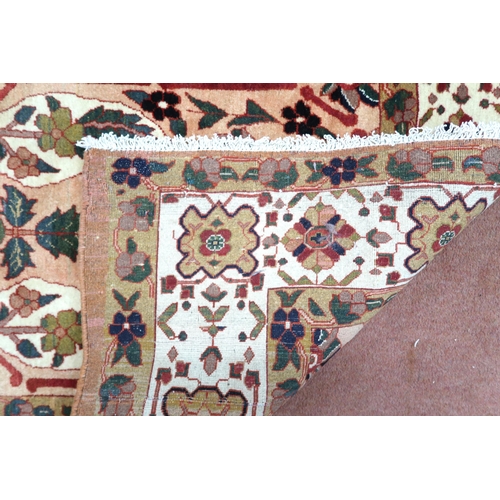 2138 - A PEACH GROUND HERIZ RUG decorated with six panelled ground with foliate and urn designs and flower ... 