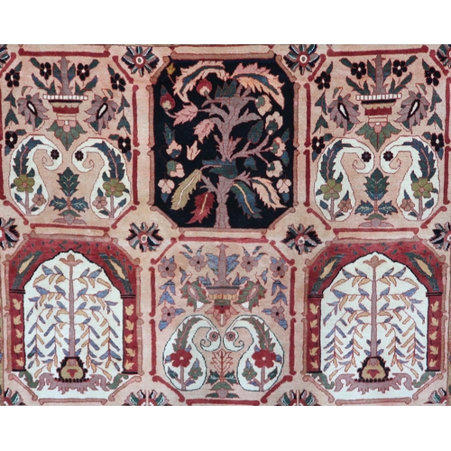 2138 - A PEACH GROUND HERIZ RUG decorated with six panelled ground with foliate and urn designs and flower ... 