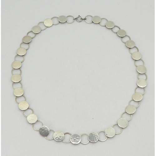 2739 - A WILHELM MULLER NECKLACEof hammered silver discs linked with rings. The end link marked with Muller... 