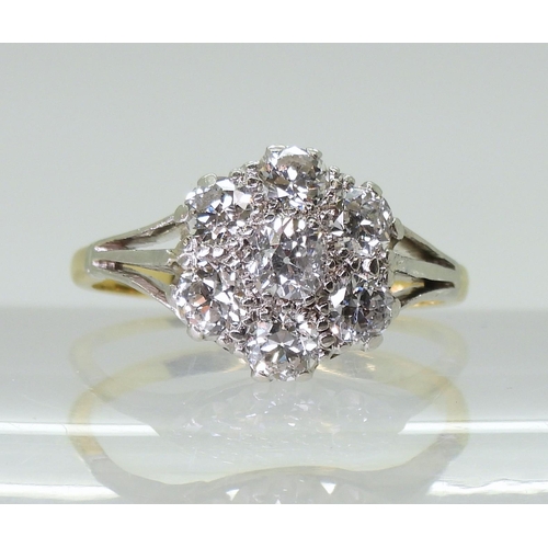 2778 - AN 18CT GOLD AND PLATINUM DIAMOND FLOWER RING with fleur de lis shoulders, set with estimated approx... 