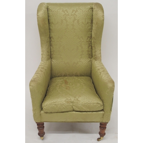 2050A - A VICTORIAN GREEN DAMASK UPHOLTERED WINGBACK ARMCHAIR with high winged back on turned front sup... 