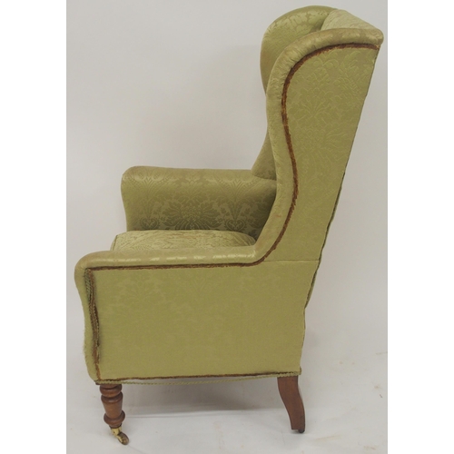 2050A - A VICTORIAN GREEN DAMASK UPHOLTERED WINGBACK ARMCHAIR with high winged back on turned front sup... 