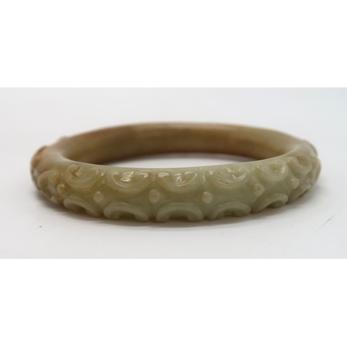 2303A - A CHINESE HARDSTONE CARVED BANGLE decorated with calligraphy,scrolls and foliage, 68 grams, 9cm... 