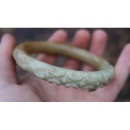 2303A - A CHINESE HARDSTONE CARVED BANGLE decorated with calligraphy,scrolls and foliage, 68 grams, 9cm... 