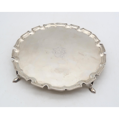 374 - A George V silver waiter, London 1928, of circular form with a chippendale-style border, on four pad... 