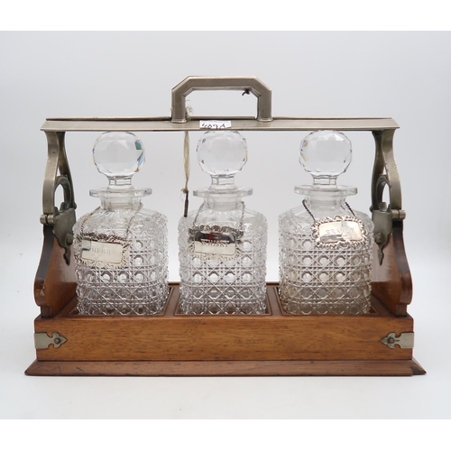 409A - A three bottle tantalus, with hobnail cut bottles and one silver 'Brandy' decanter label, an EPNS 'S... 