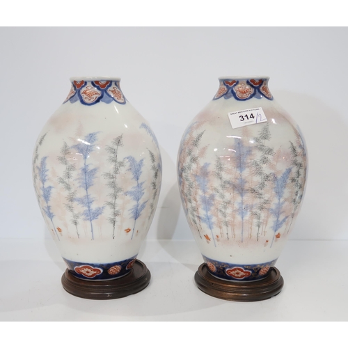 314 - A pair of Japanese Imari vases, of baluster form, decorated with trees, with bands of lozenges, on h... 