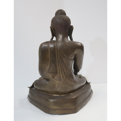 323 - A 20th century Burmese cast bronze Shakyamuni buddha, seated in lotus pose, wearing folded and pleat... 