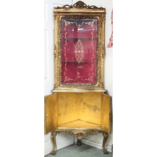 26 - A 20th century gilt Rococo style glazed corner cabinet with scrolled surmount over single glazed doo... 