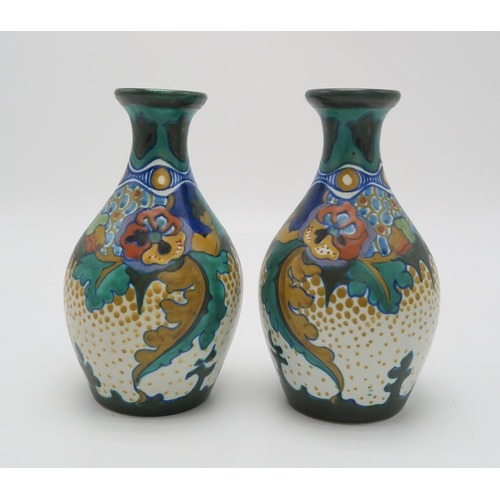 2153 - A PAIR OF GOUDA POTTERY VASESof bottle form painted with flowers and foliage, with painted marks and... 