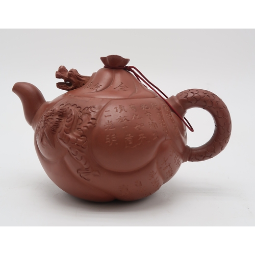 2355 - A YIXING TEAPOT AND COVERWith articulated dragon cover above calligraphy, fish and dragon, 16cm wide... 