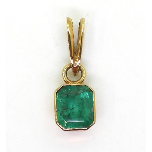 797 - A bright yellow metal mounted emerald pendant. Set with a step cut emerald of estimated approx 6.5mm... 