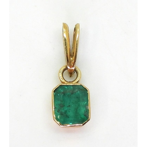 797 - A bright yellow metal mounted emerald pendant. Set with a step cut emerald of estimated approx 6.5mm... 