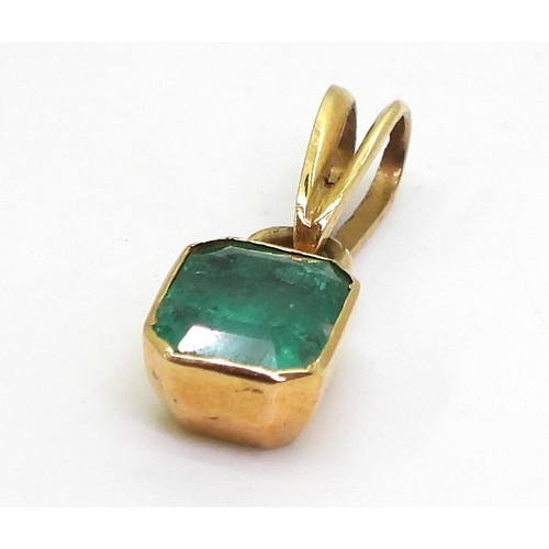 797 - A bright yellow metal mounted emerald pendant. Set with a step cut emerald of estimated approx 6.5mm... 