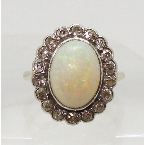 801 - A white opal & diamond cluster ring, mounted in white metal, set with a central oval cabochon op... 