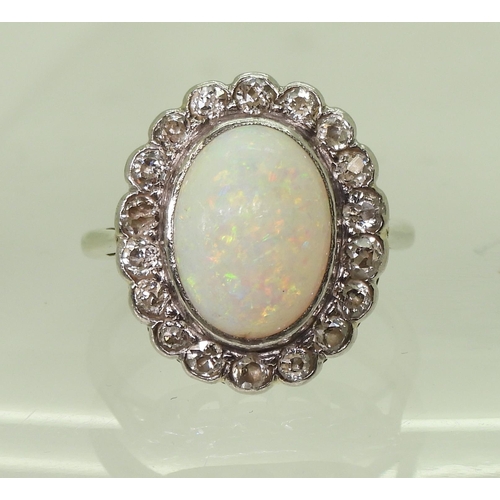 801 - A white opal & diamond cluster ring, mounted in white metal, set with a central oval cabochon op... 