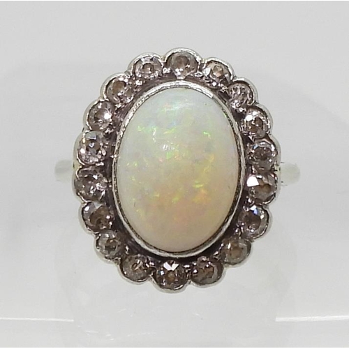 801 - A white opal & diamond cluster ring, mounted in white metal, set with a central oval cabochon op... 