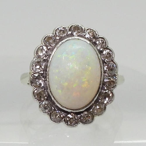 801 - A white opal & diamond cluster ring, mounted in white metal, set with a central oval cabochon op... 