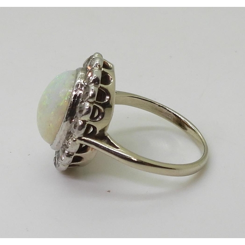 801 - A white opal & diamond cluster ring, mounted in white metal, set with a central oval cabochon op... 