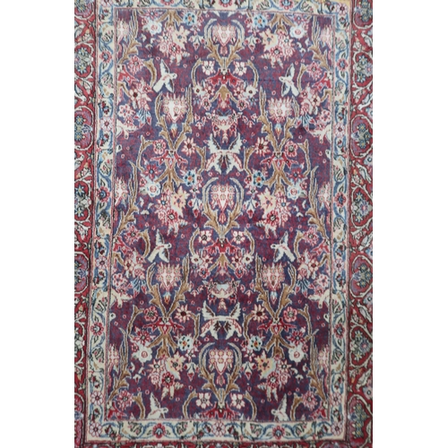 44 - An extensively decorated patterned ground Indian Kerman rug with multicoloured borders depicting bir... 