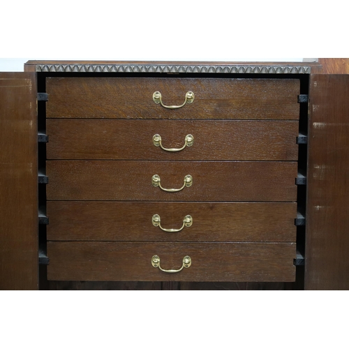 76 - An early 20th century oak cabinet with pair of cabinet doors concealing five drawers over open shelf... 