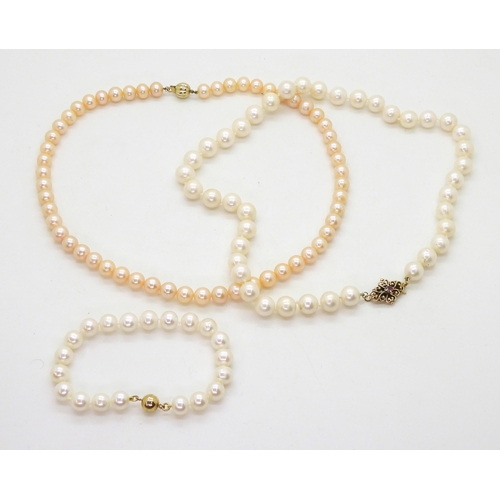 774 - A string of large pearls each approx 9.5mm, with a 9ct gold decorative clasp set with a red gem, tog... 