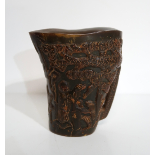 278A - A Chinese carved horn libation cup, depicting figures amongst pine trees, a carved model of Buddha, ... 