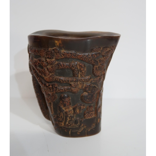 278A - A Chinese carved horn libation cup, depicting figures amongst pine trees, a carved model of Buddha, ... 