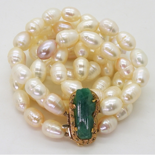 2731 - AN EMERALD AND PEARL NECKLACEthe bright yellow metal clasp is set with a natural raw emerald crystal... 