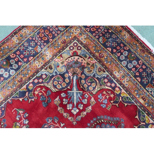 2131 - A RED GROUND TABRIZ RUGwith dark blue and beige flower head central medallion, matching spandrels an... 
